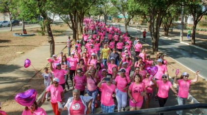 imagem de varias mulheres com blusa rosa em uma caminhada em prol do outubro rosa.